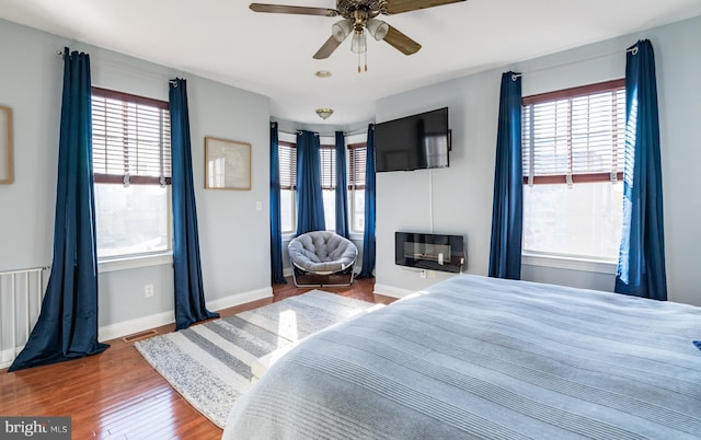 bedroom with hardwood / wood-style floors, multiple windows, and ceiling fan