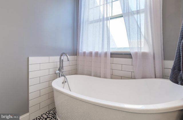 bathroom featuring a bath and tile walls