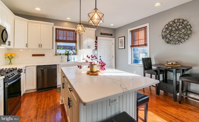 kitchen with a wealth of natural light, black appliances, a kitchen bar, and a kitchen island