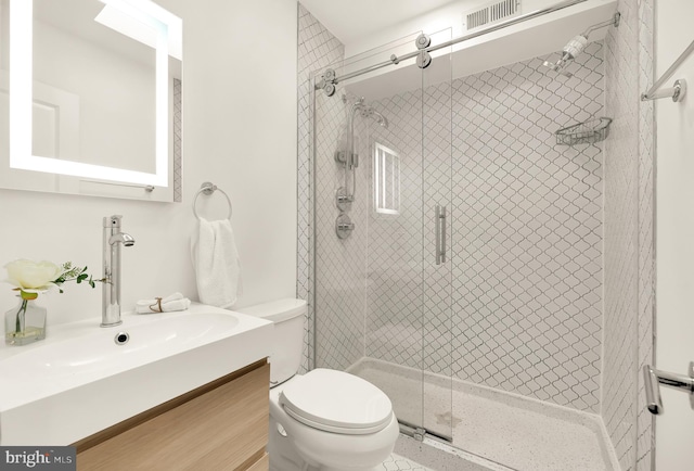 bathroom featuring vanity, a shower with shower door, and toilet