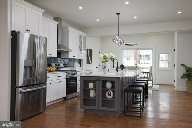 kitchen featuring wall chimney exhaust hood, white cabinets, and appliances with stainless steel finishes