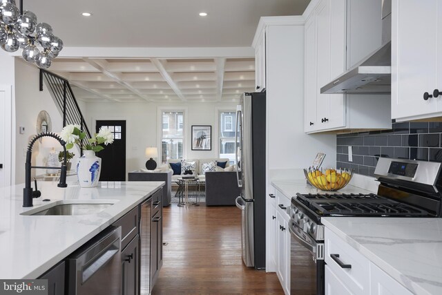 kitchen featuring white cabinets, wall chimney exhaust hood, appliances with stainless steel finishes, and coffered ceiling