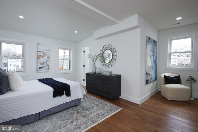 bedroom with beamed ceiling, dark hardwood / wood-style floors, and multiple windows