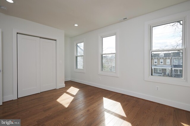 unfurnished bedroom with a closet and dark wood-type flooring