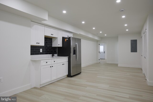 kitchen featuring tasteful backsplash, light hardwood / wood-style flooring, stainless steel fridge with ice dispenser, electric panel, and white cabinetry