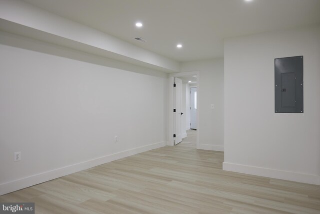 unfurnished room with electric panel and light hardwood / wood-style flooring