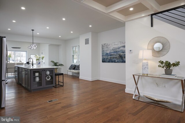 kitchen featuring sink, hanging light fixtures, dark hardwood / wood-style floors, an island with sink, and a breakfast bar area