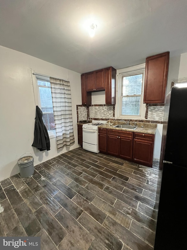 kitchen with dark hardwood / wood-style floors, tasteful backsplash, sink, fridge, and white range oven