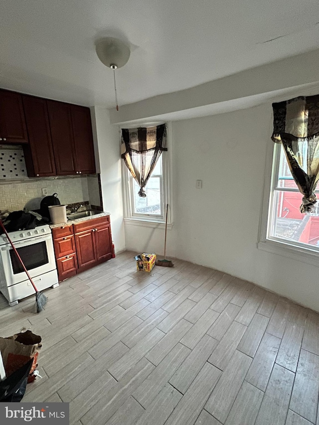 kitchen featuring a healthy amount of sunlight, white range oven, light hardwood / wood-style flooring, and tasteful backsplash