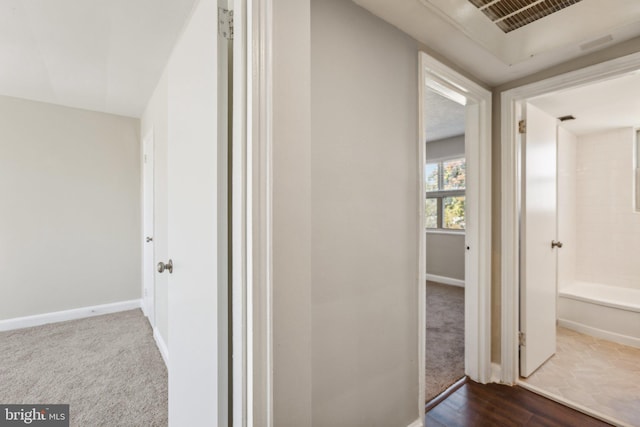 hallway featuring dark wood-style flooring, dark carpet, and baseboards