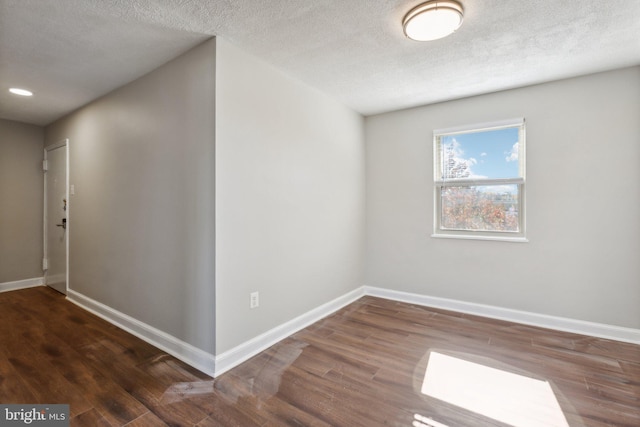 empty room with a textured ceiling and dark hardwood / wood-style flooring