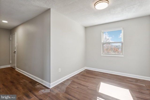 spare room featuring a textured ceiling, wood finished floors, recessed lighting, and baseboards