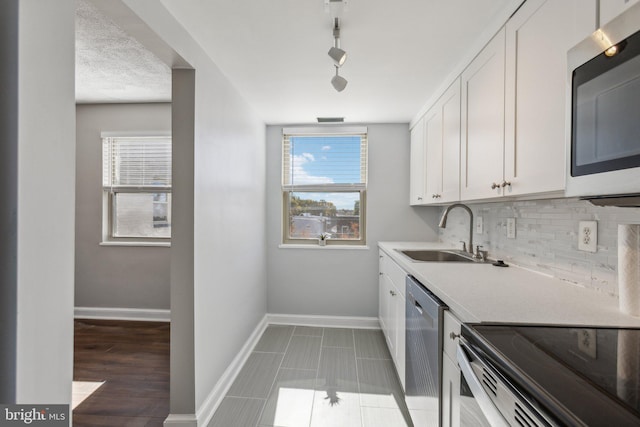 kitchen featuring sink, appliances with stainless steel finishes, white cabinetry, and plenty of natural light