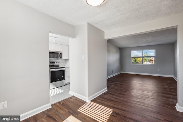 kitchen featuring appliances with stainless steel finishes, a textured ceiling, dark hardwood / wood-style floors, and white cabinets