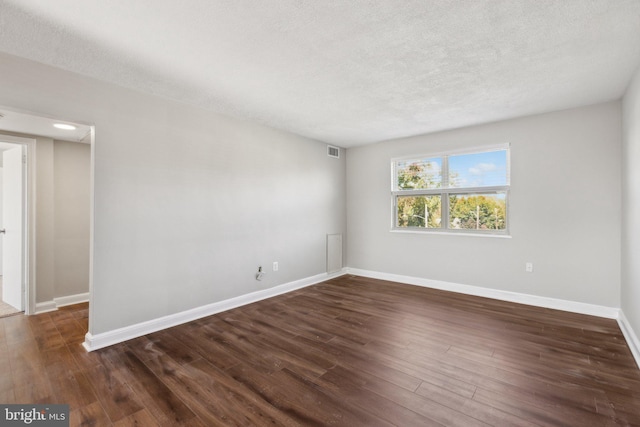 spare room featuring a textured ceiling and dark hardwood / wood-style flooring