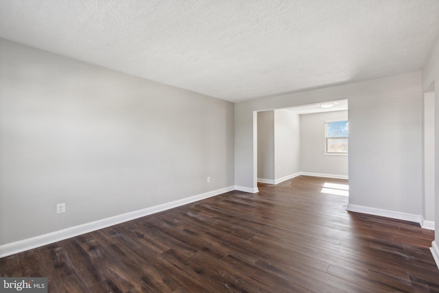 spare room featuring a textured ceiling and dark wood-type flooring