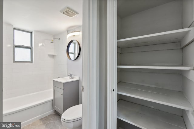 full bathroom featuring tiled shower / bath, vanity, toilet, and tile patterned flooring