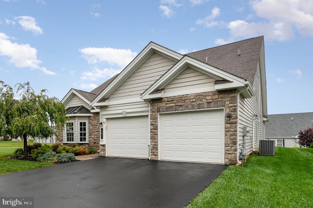 view of front of property with a garage, central air condition unit, and a front lawn