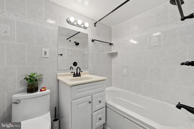 full bathroom featuring tile walls, tiled shower / bath combo, vanity, and toilet