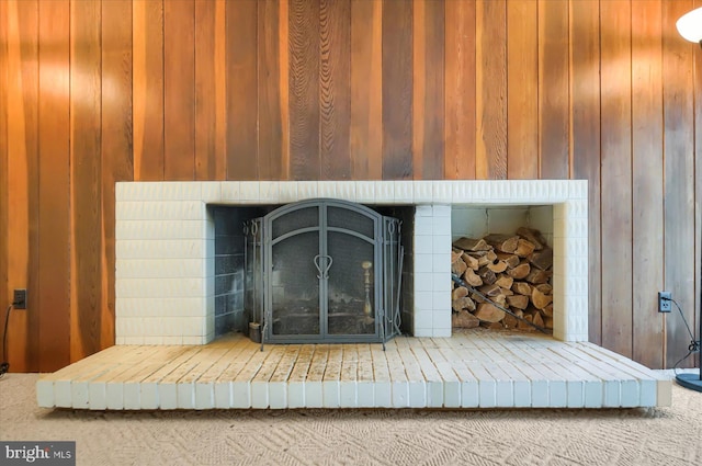 room details with a brick fireplace, wood walls, and carpet