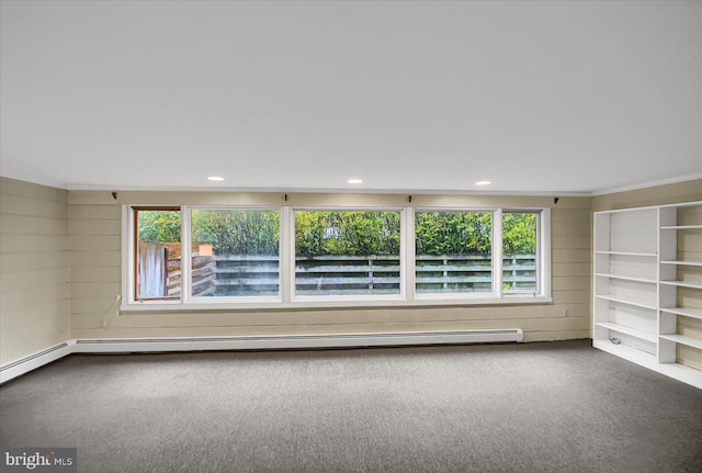 carpeted spare room with ornamental molding, wood walls, and baseboard heating