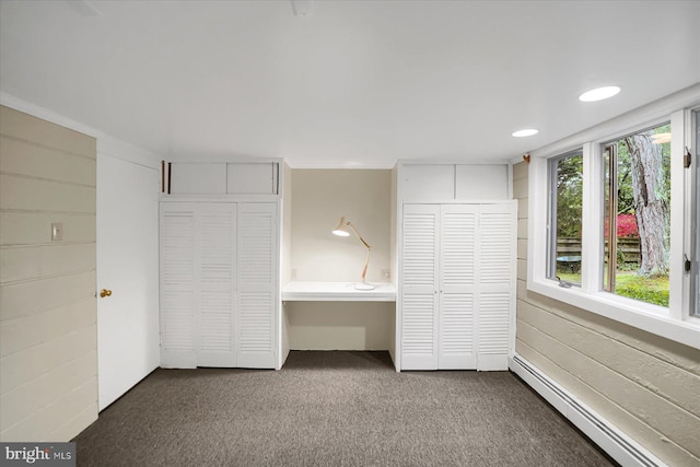 unfurnished bedroom with multiple closets, baseboard heating, and carpet flooring