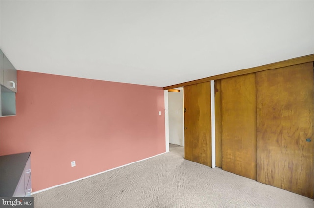 unfurnished bedroom with light colored carpet and a closet