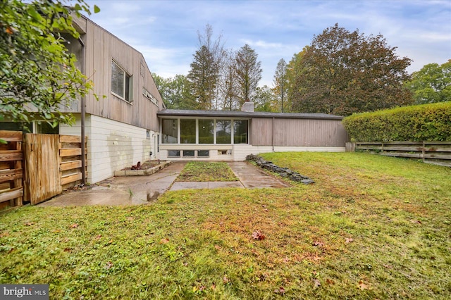 rear view of property with a yard and a sunroom