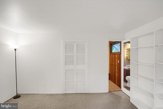 unfurnished bedroom with connected bathroom and light carpet