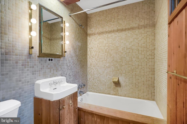 full bathroom featuring tile walls, tiled shower / bath, vanity, and toilet