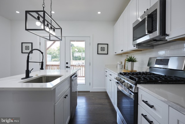 kitchen featuring pendant lighting, an island with sink, dark wood-type flooring, white cabinetry, and appliances with stainless steel finishes