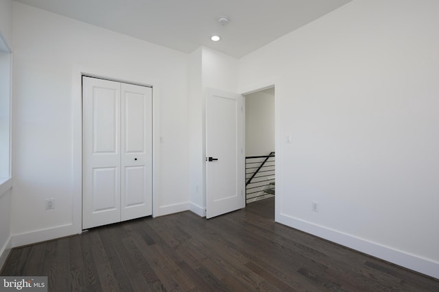 unfurnished bedroom with a closet and dark hardwood / wood-style flooring