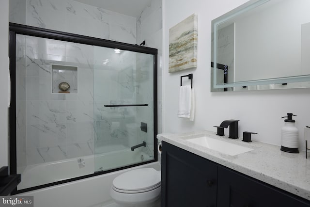 full bathroom with enclosed tub / shower combo, vanity, and toilet