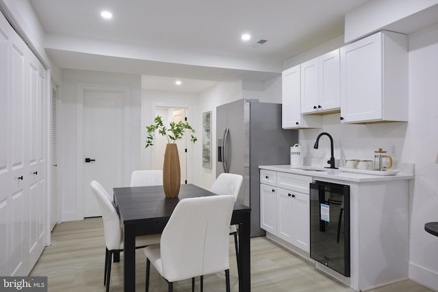 kitchen featuring light hardwood / wood-style flooring, white cabinets, black dishwasher, and sink