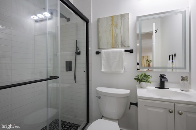 bathroom with a shower with shower door, vanity, and toilet