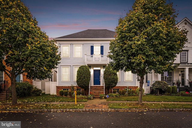 view of front of house with a yard and a balcony