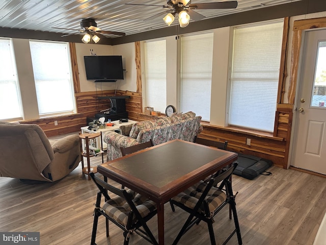 dining area with wooden walls, ceiling fan, and hardwood / wood-style floors