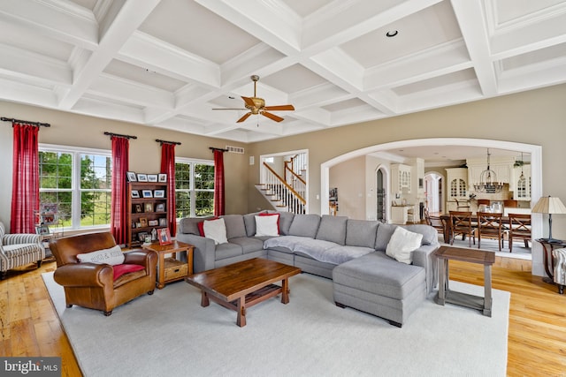 living room featuring beamed ceiling, coffered ceiling, hardwood / wood-style floors, ornamental molding, and ceiling fan