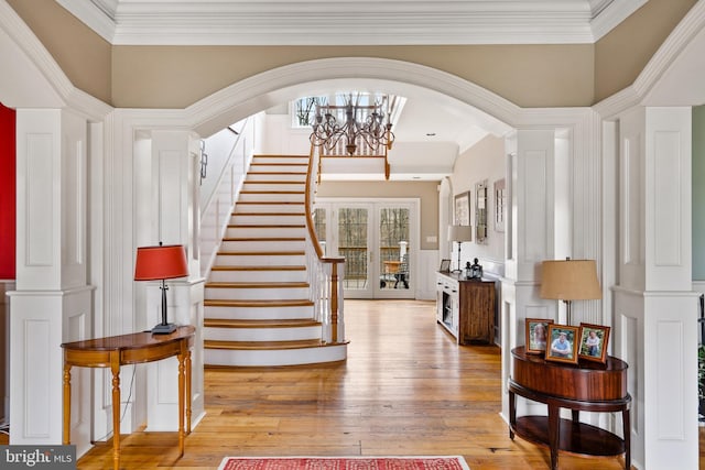 foyer featuring an inviting chandelier, crown molding, light hardwood / wood-style floors, and a high ceiling