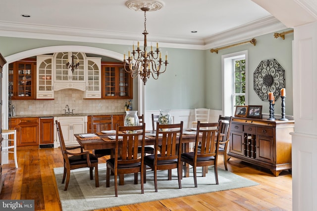 dining room featuring a chandelier, crown molding, hardwood / wood-style floors, and sink