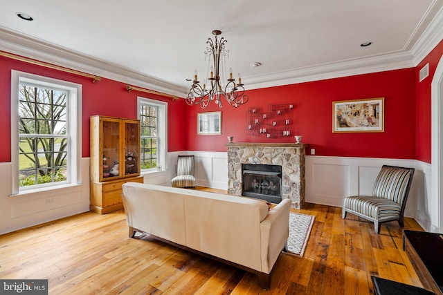 living room with a fireplace, crown molding, a chandelier, and light hardwood / wood-style flooring