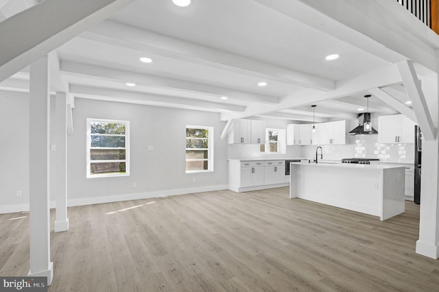 kitchen with a center island, beamed ceiling, white cabinets, and light wood-type flooring