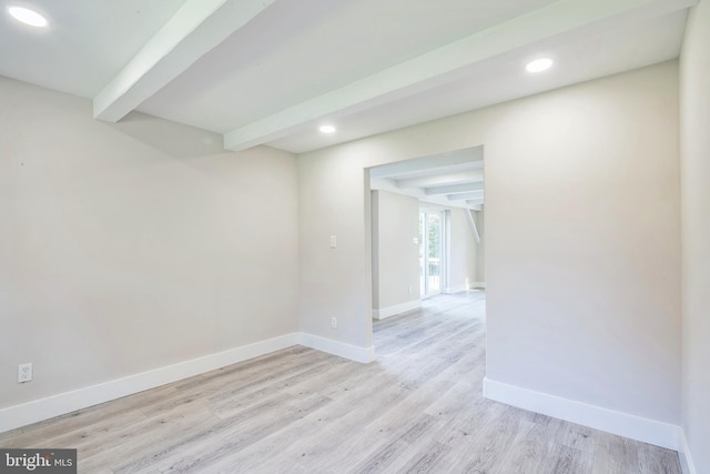 empty room featuring beamed ceiling and light wood-type flooring