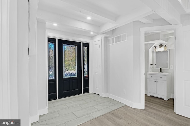 entryway featuring beamed ceiling, sink, and light hardwood / wood-style flooring