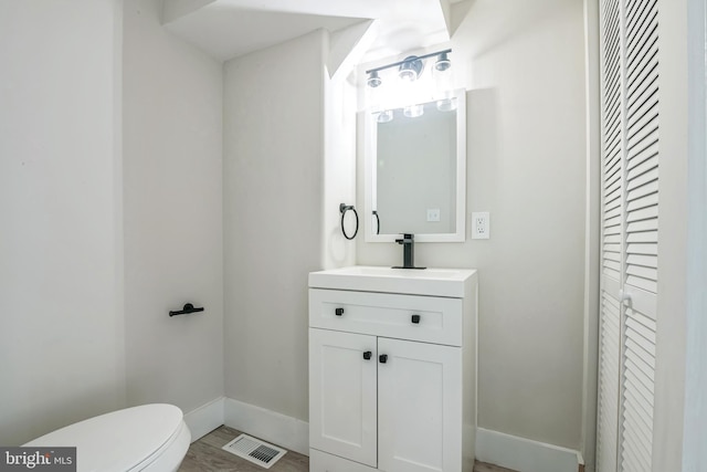 bathroom with vanity, toilet, and wood-type flooring