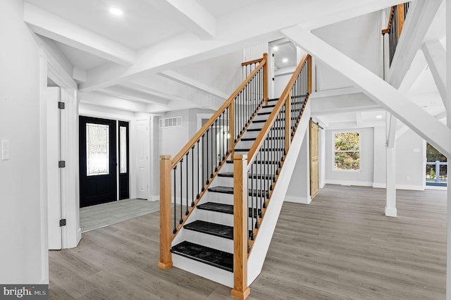 foyer entrance featuring a barn door, light wood-type flooring, and beam ceiling