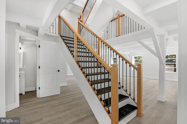 staircase featuring beamed ceiling and wood-type flooring