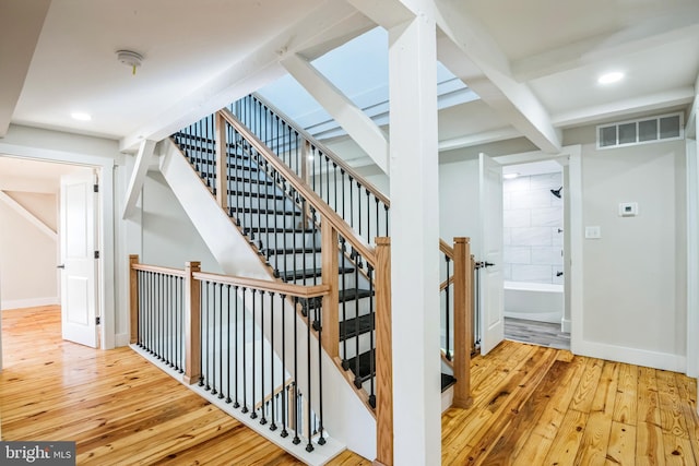 stairs with beam ceiling and hardwood / wood-style floors