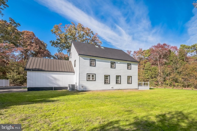 rear view of property with a lawn and central AC