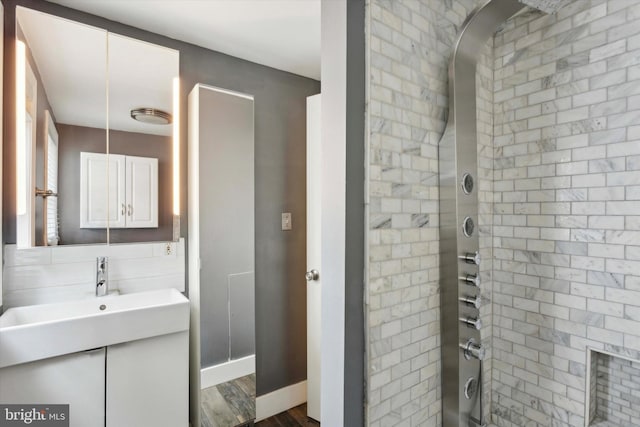 bathroom with hardwood / wood-style floors, vanity, and tiled shower